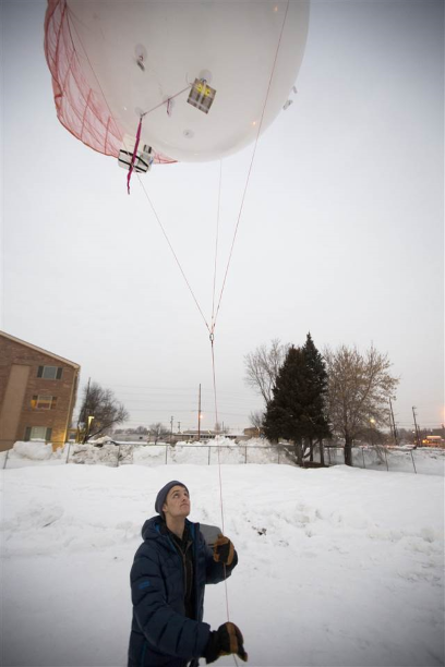 A large research balloon floating above me while I hold the tether.