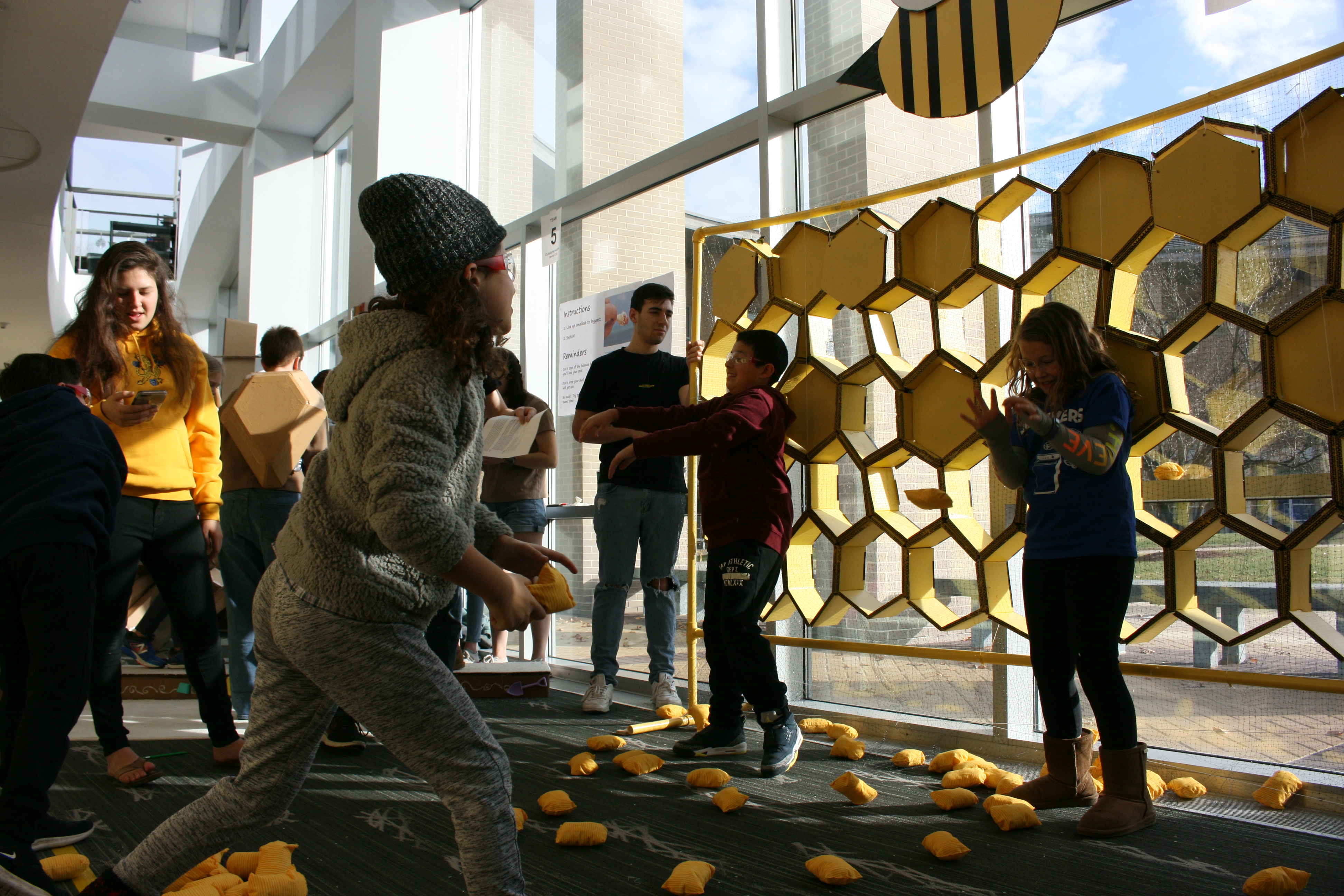 An image of children playing a game with a wall of yellow hexagons
					about 30 centimeters in size.